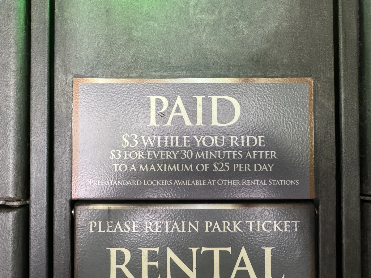 Paid locker rates sign at Universal Orlando showing $3 while you ride, $3 for every 30 minutes after, with a $25 maximum per day