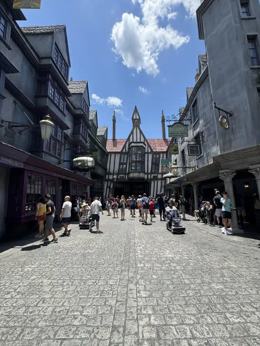 Walking down Diagon Alley with half-timbered storefronts and guests browsing in the Wizarding World of Harry Potter at Universal Studios Florida.