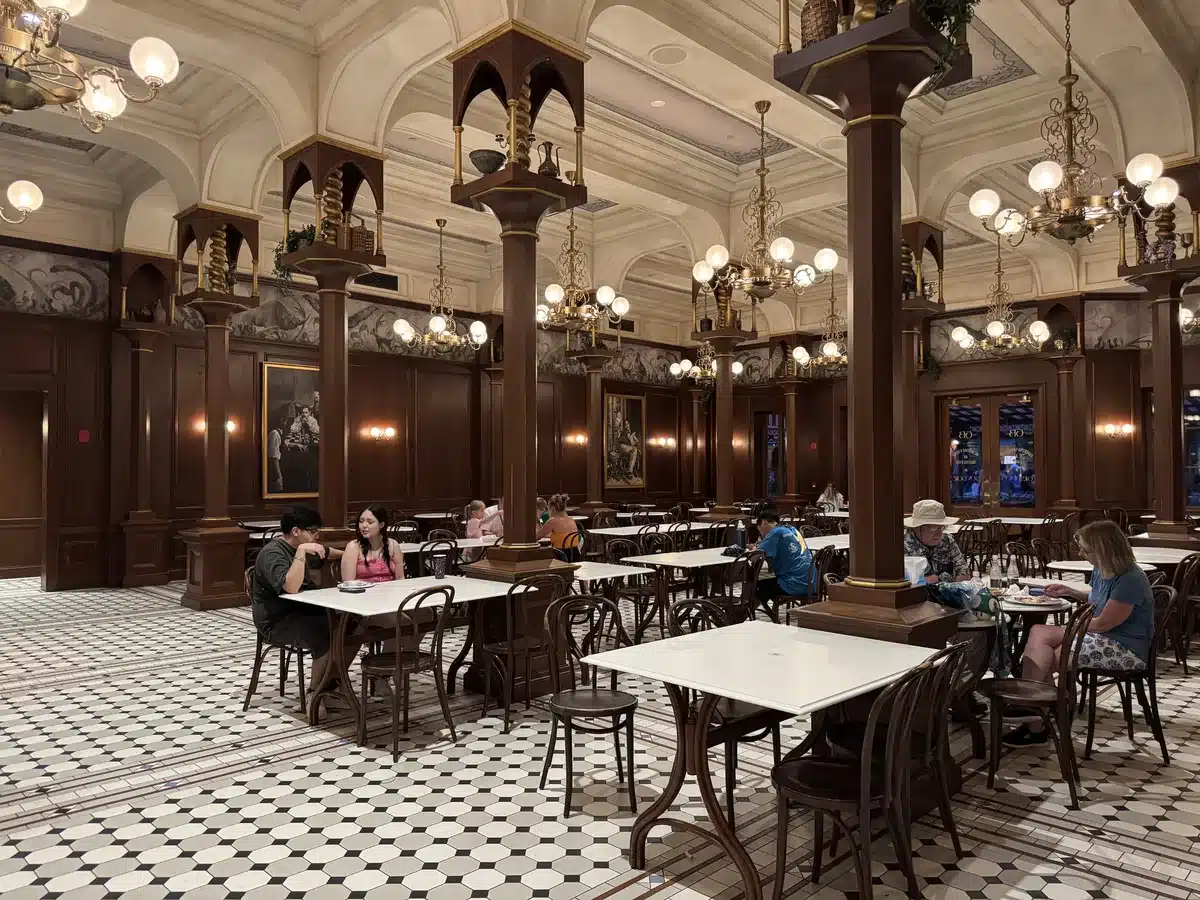 Café L’Air De La Sirène French bistro interior with marble columns and chandeliers at Place Cachée Wizarding World of Harry Potter Epic Universe.