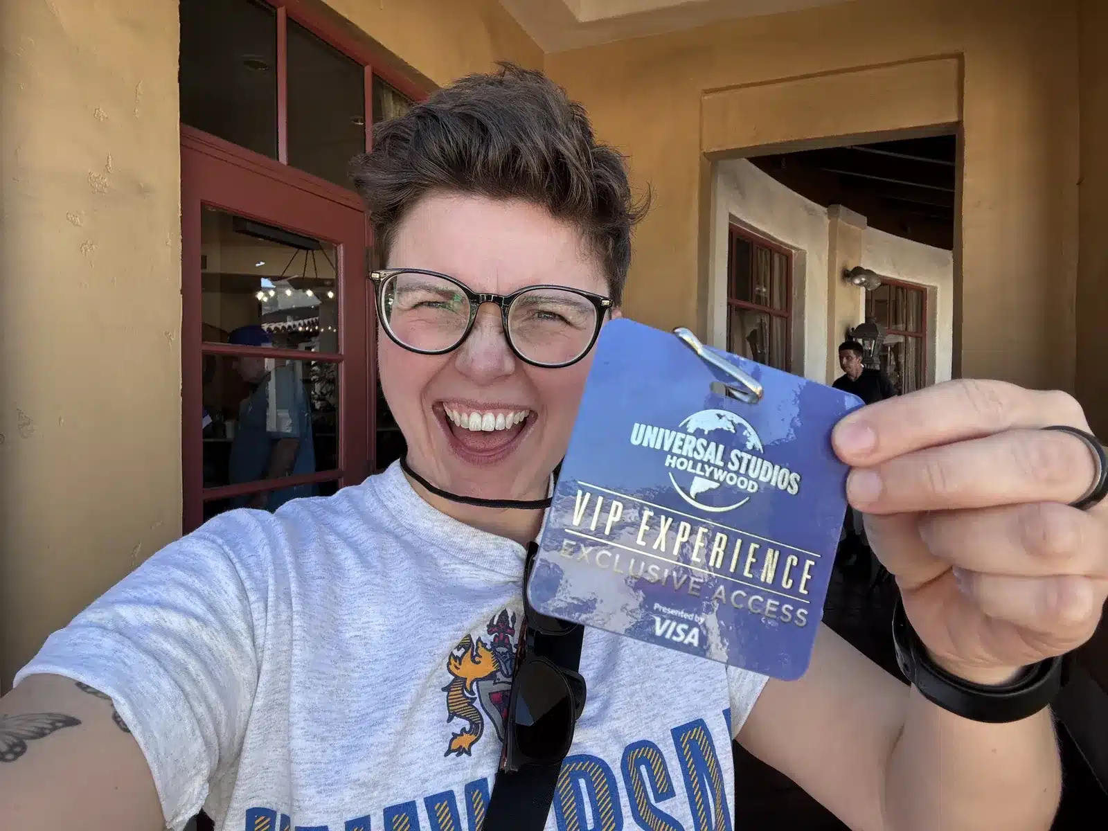 Cora holding up the blue VIP Experience exclusive access badge outside the VIP entrance at Universal Studios Hollywood