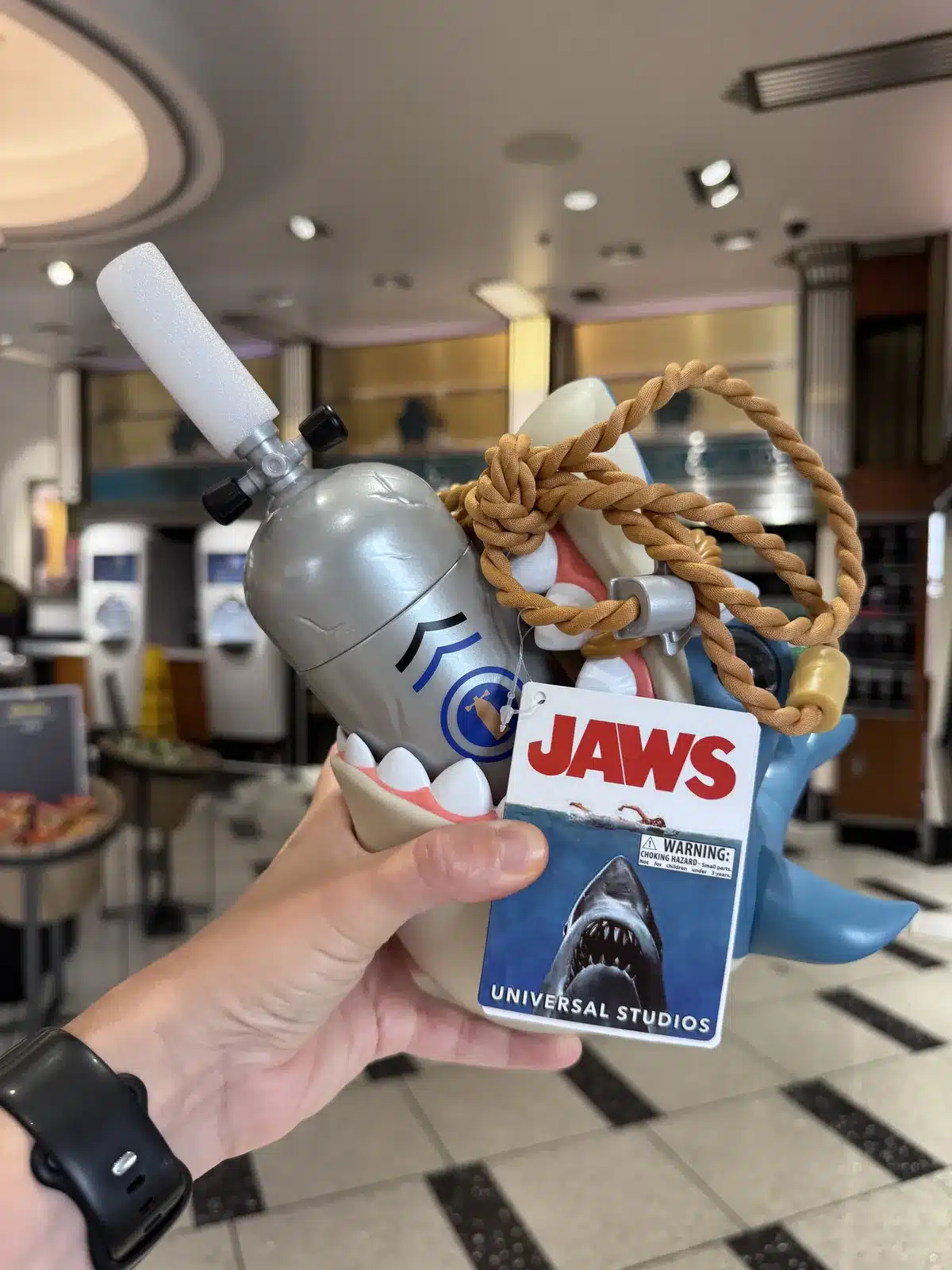 Jaws souvenir sipper cup shaped like a shark, held up inside Studio Cafe at Universal Studios Hollywood