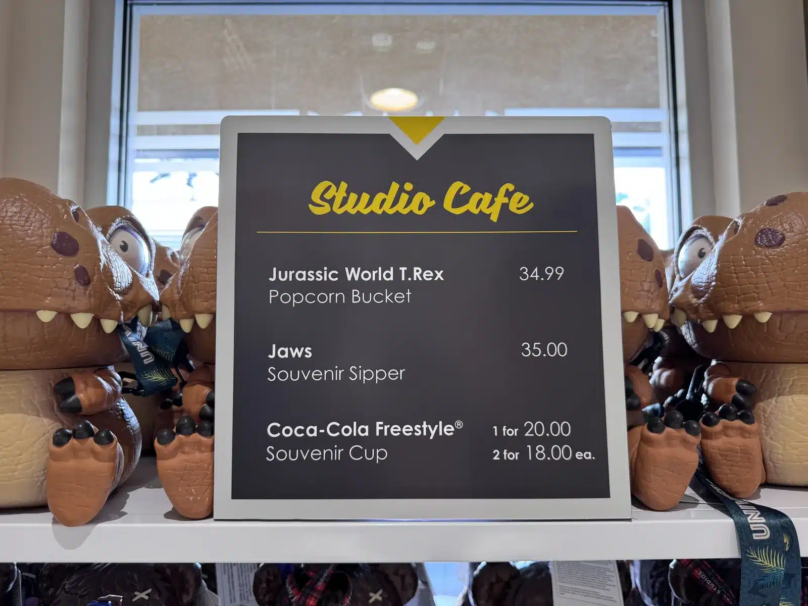 Studio Cafe price board at Universal Studios Hollywood listing the Jaws souvenir sipper at $35 and the Coca-Cola Freestyle cup at $20