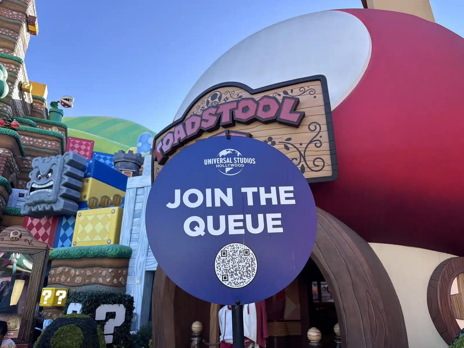Toadstool Cafe join the queue sign outside the mushroom-roofed restaurant in Super Nintendo World at Universal Studios Hollywood