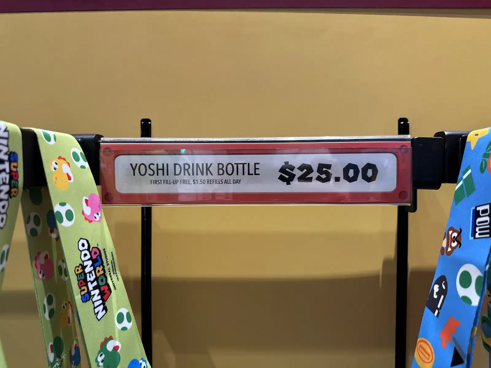 Yoshi drink bottle price sign in Super Nintendo World at Universal Studios Hollywood showing $25 with the first fill free and $1.50 refills
